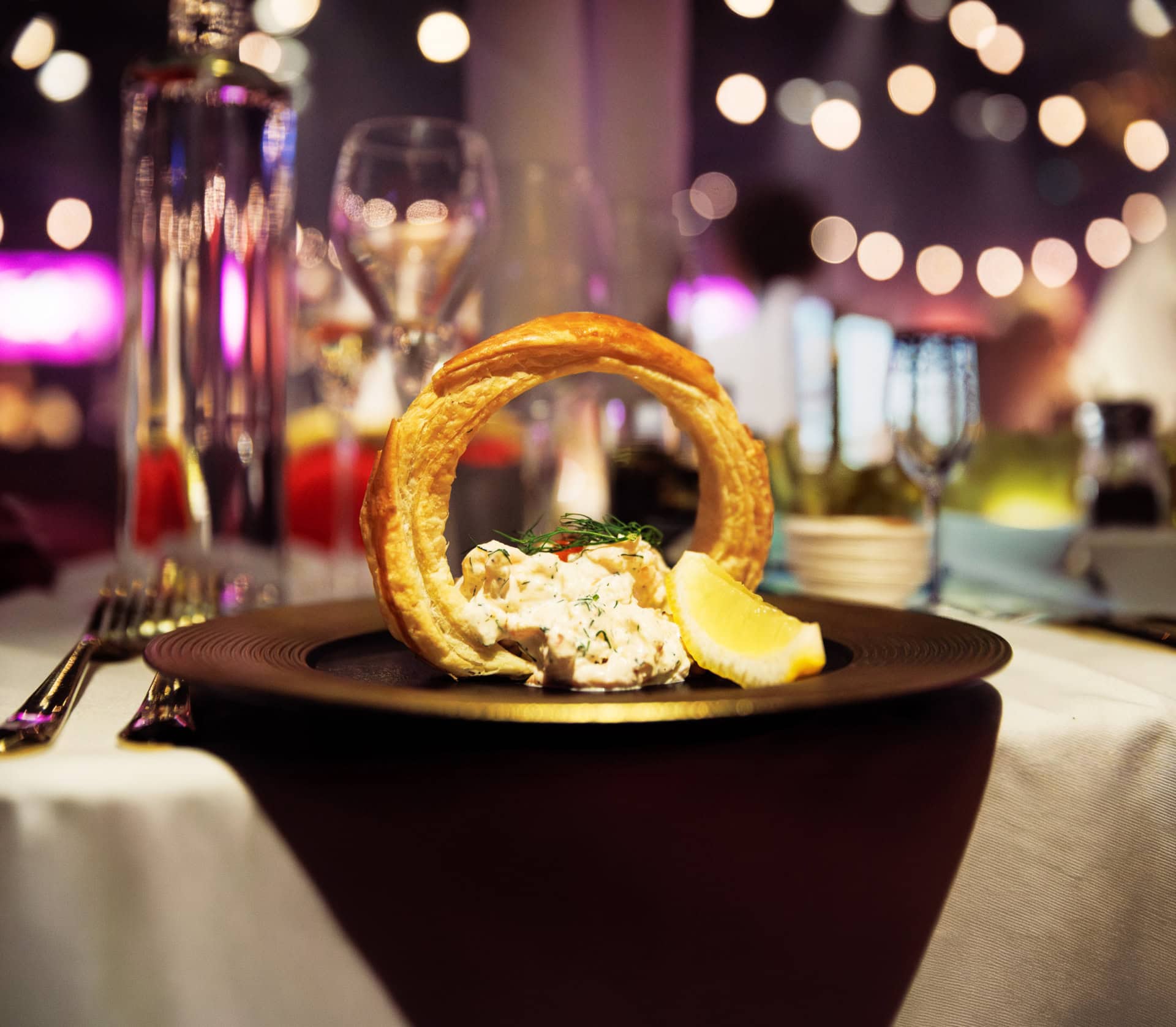 Friterad fiskrätt med citron och sallad på elegant restaurangbord.